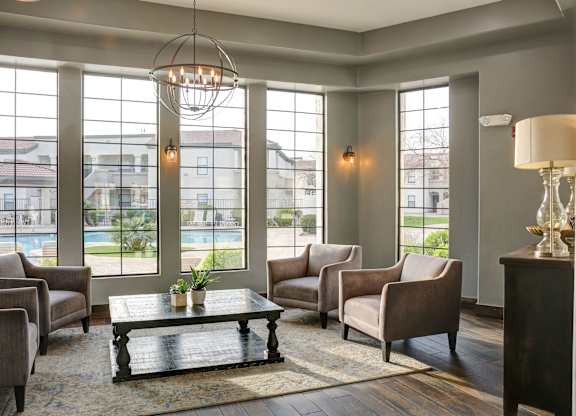 A living room with a large window and a view of a pool and houses.