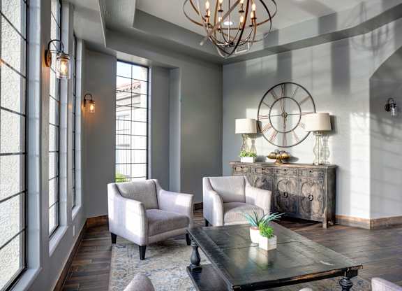 A living room with a chandelier, two chairs, a table, and a sideboard.
