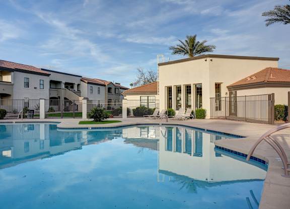A swimming pool in front of a building with a palm tree in the background.