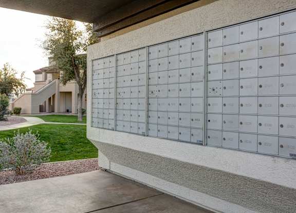 A row of mailboxes are lined up on the side of a building.