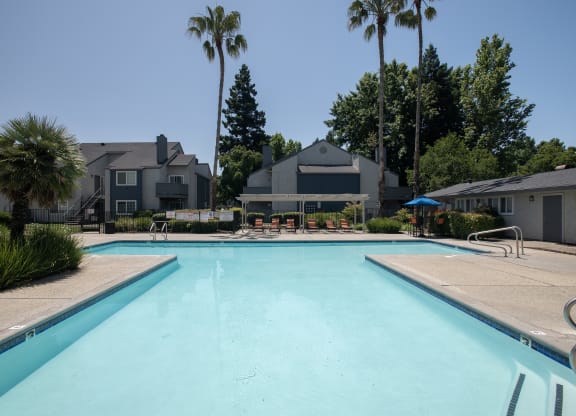 swimming pool and pool deck with  lounge chairs and umbrellas at Woodbridge Apartments, Sacramento, California 95833
