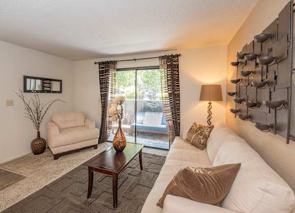 A living room with a white couch, a brown pillow, and a brown vase at Bishop's Court Apartments, California, 95670