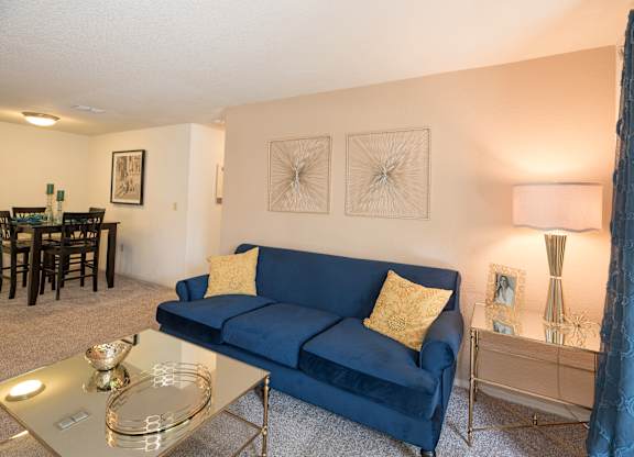 A blue couch with a yellow pillow sits in a living room at Bishop's Court Apartments, California, 95670