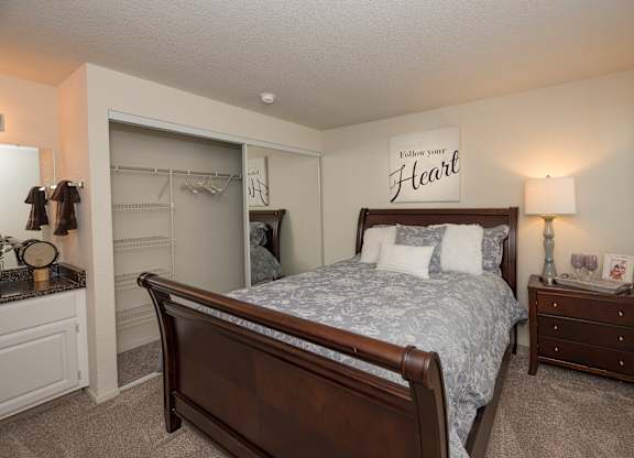 A bedroom with a bed, nightstand, and a wall hanging that says