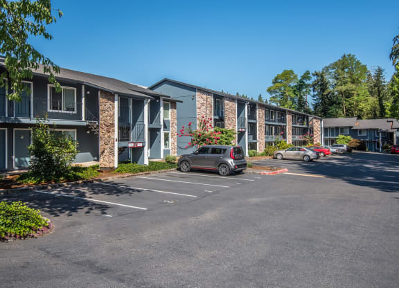 Cedar Lane Apartments two and three story building fronts and parking lot with numbered spaces.