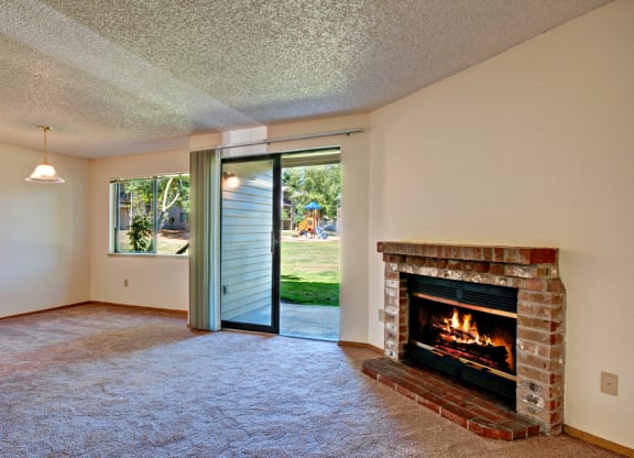 Apartment Living Room With Fireplace & Patio Sliding Door at Chambers Creek Estates, University Place, Washington 98467