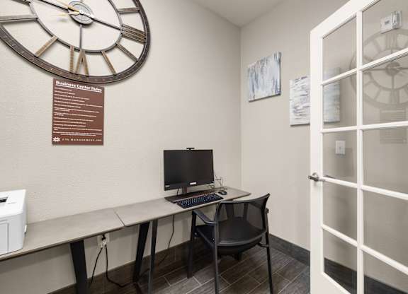 A business center with a desk, a computer, and a clock on the wall at Clackamas Trails Apartments, Oregon, 97222