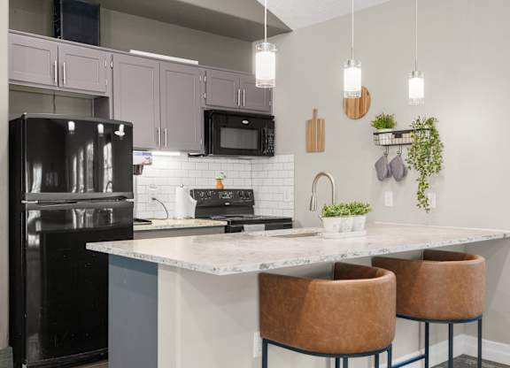 Clubhouse kitchen with a black refrigerator, a white countertop, and brown chairs at Clackamas Trails Apartments, Oregon, 97222
