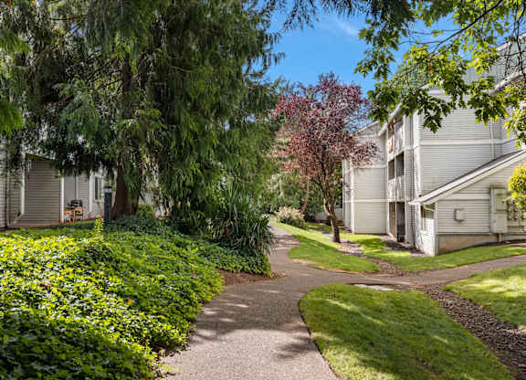 An apartment common area with a pathway and greenery at Clackamas Trails Apartments, Oregon, 97222