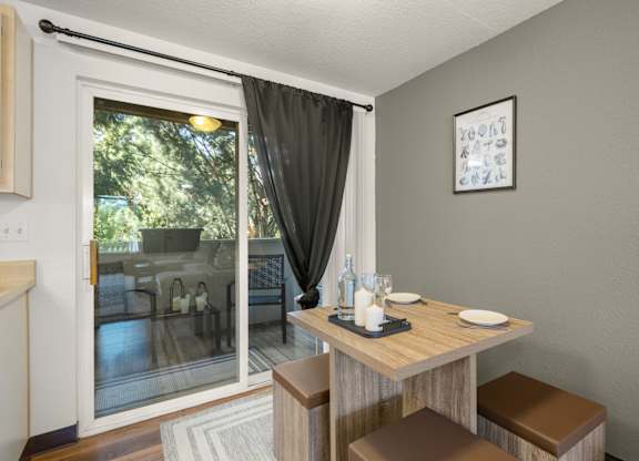A dining area with a table set for two and a view of trees at Clackamas Trails Apartments, Oregon, 97222