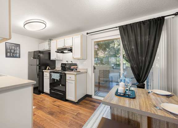 Model kitchen and dining area with a table and sliding glass door at Clackamas Trails Apartments, Oregon, 97222