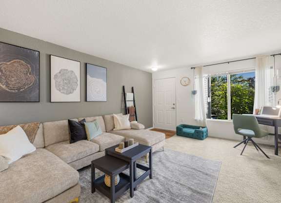 A living room with a beige couch, a coffee table, and a green pet bed at Clackamas Trails Apartments, Oregon, 97222