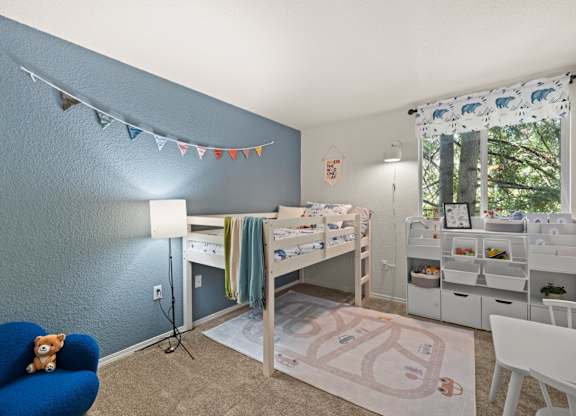 A room with a blue chair and a white and bed frame and desk with a computer at Clackamas Trails Apartments, Oregon, 97222