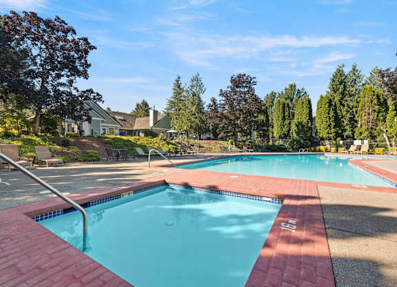 A small and large swimming pool surrounded by trees and a building in the background at Clackamas Trails Apartments, Oregon, 97222
