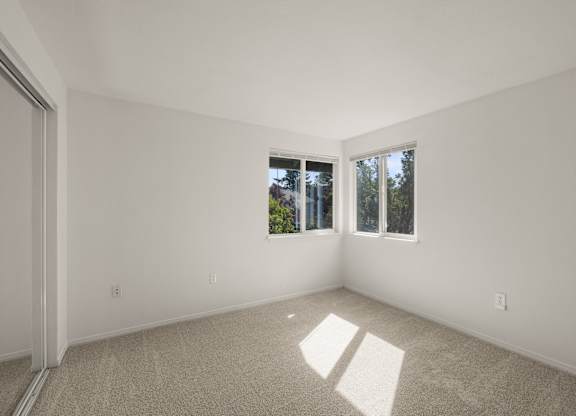 A room with a carpeted floor and two windows letting in natural light at Clackamas Trails Apartments, Oregon, 97222