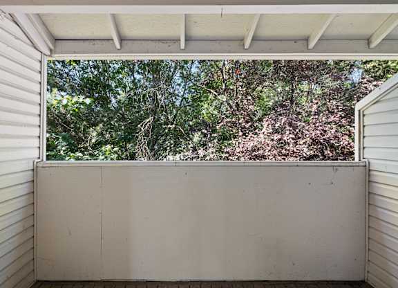 A view of trees through an apartment deck at Clackamas Trails Apartments, Oregon, 97222