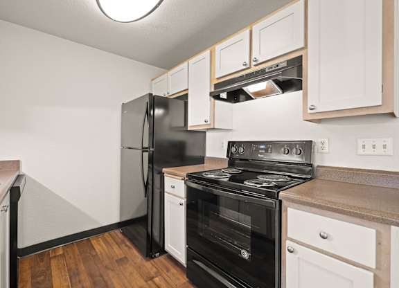 A kitchen with black and white appliances and vinyl wood grain floors at Clackamas Trails Apartments, Oregon, 97222