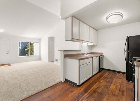 A kitchen with white cabinets and a black fridge at Clackamas Trails Apartments, Oregon, 97222