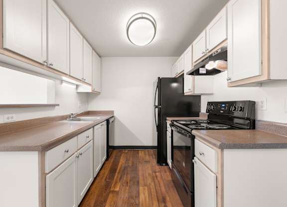 A kitchen with white cabinets and a black fridge at Clackamas Trails Apartments, Oregon, 97222