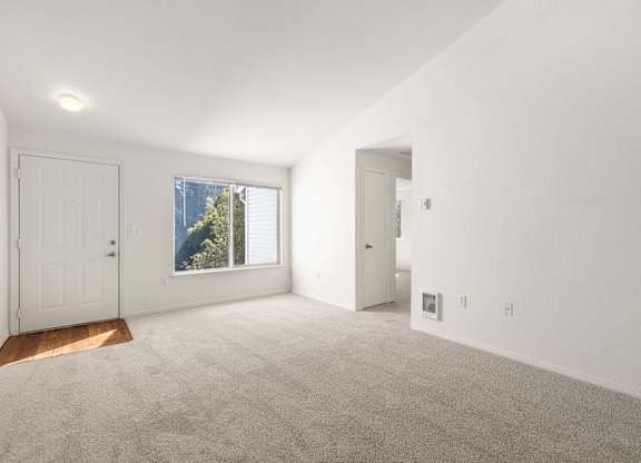 Living room with white walls and carpeted floor with a window and two doors at Clackamas Trails Apartments, Oregon, 97222