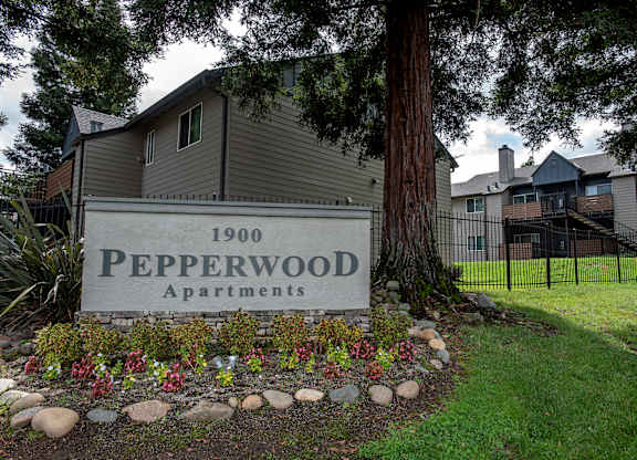 A sign for Pepperwood Apartments is in front of a tree at Pepperwood Apartments, California, 95661