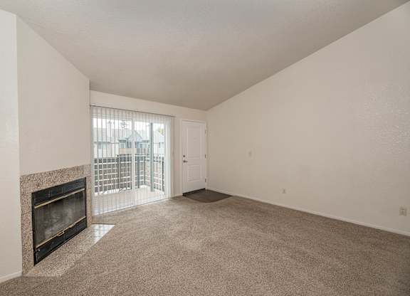 A large, empty room with a fireplace and a sliding glass door at Pepperwood Apartments, California, 95661