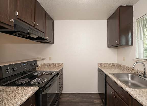 A kitchen with a black stove top oven and a counter top at Pepperwood Apartments, California, 95661