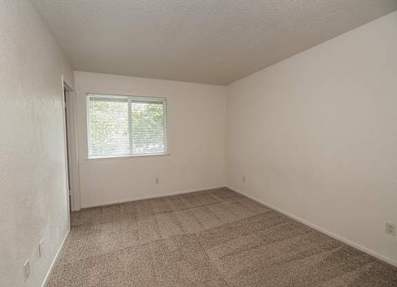 A room with a carpeted floor and a window at Pepperwood Apartments, California, 95661