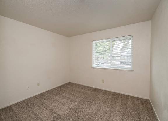 A room with a carpeted floor and a window with blinds at Pepperwood Apartments, California, 95661