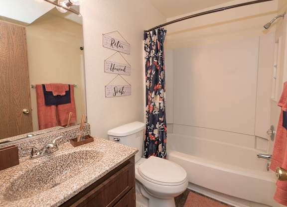 Model hallway bathroom with a toilet, sink, and a shower curtain at Pheasant Pointe Apartments, California, 95833