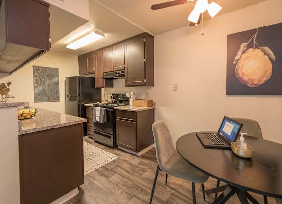 Model kitchen with a table and chairs and a laptop on it  at Pheasant Pointe Apartments, California, 95833