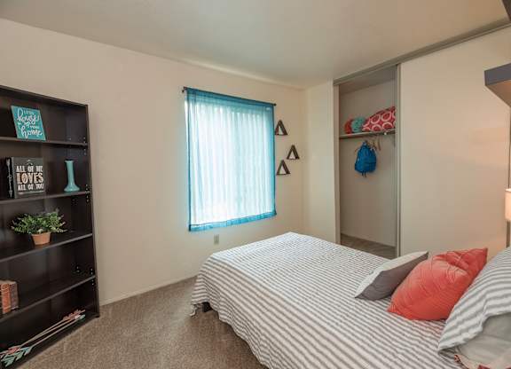 Model second bedroom with a bed, a bookshelf, and a window with a blue curtain at Pheasant Pointe Apartments, California, 95833