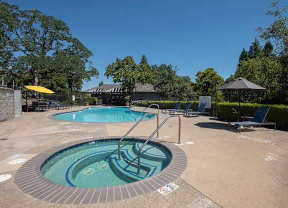 A hot tub sits in the middle of a patio surrounded by trees at Rocklin Gold Apartments, California, 95677