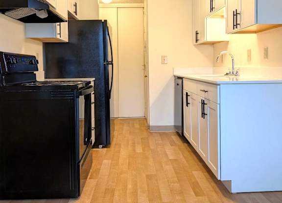 Rolling Hills Apartments upgraded kitchen with black appliances, white cabinets, and vinyl plank flooring