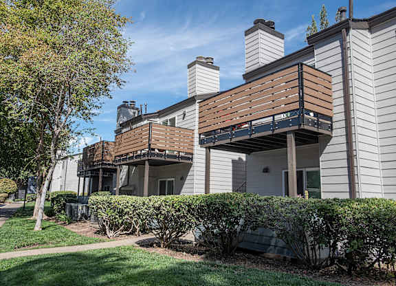An apartment building with a balcony and a tree in front at Sierra Glen Apartments, California, 95621