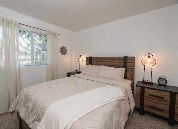 A bedroom with a large bed and two lamps on either side of the bed at Sierra Glen Apartments, California, 95621