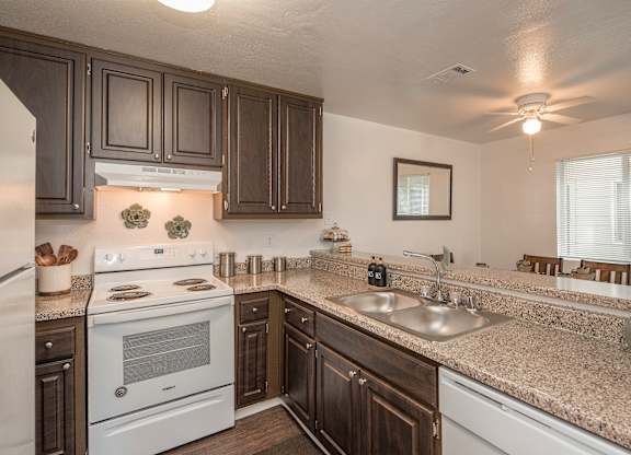 A kitchen with a white stove and brown cabinets at Sierra Glen Apartments, California, 95621