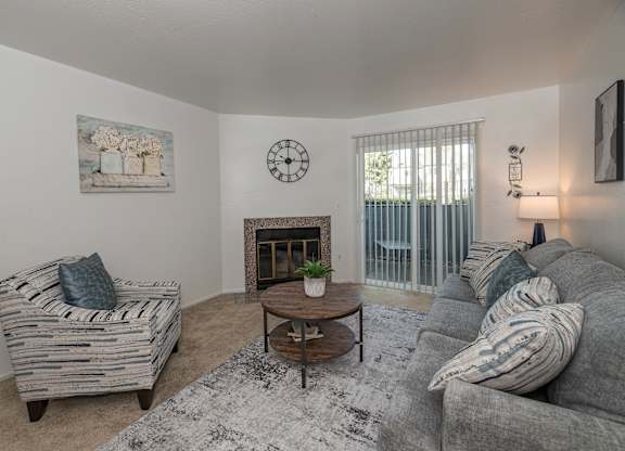 A living room with a grey couch, a wooden coffee table, and a painting on the wall at Sierra Glen Apartments, California, 95621