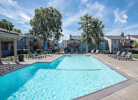 A large swimming pool surrounded by lounge chairs and trees at Sierra Glen Apartments, California, 95621