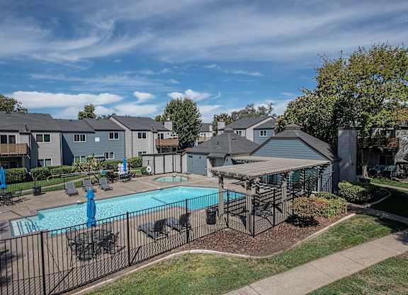A pool surrounded by a fence and chairs at Sierra Glen Apartments, California, 95621