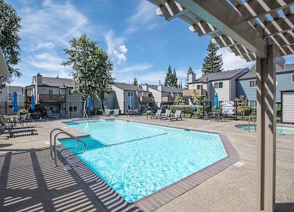 A large swimming pool with a shaded area next to it at Sierra Glen Apartments, California, 95621