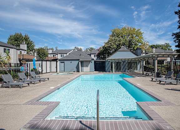 A swimming pool surrounded by lounge chairs and trees at Sierra Glen Apartments, California, 95621