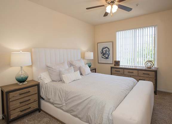 A bedroom with a large bed, two lamps, and a ceiling fan at Stoneridge Apartments, California, 95661