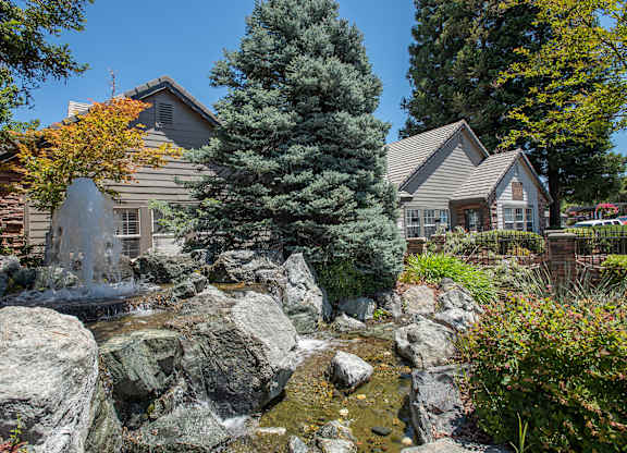 A clubhouse with a waterfall in front of it at Sunset Summit, Rocklin, CA, 95765