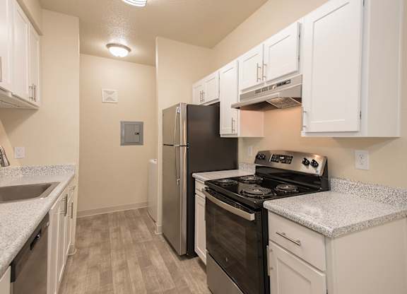 A kitchen with white cabinets and a black refrigerator at Sunset Summit, Rocklin, CA, 95765