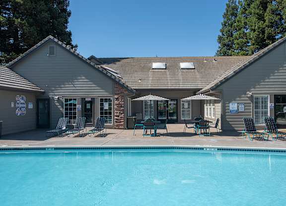 A swimming pool is surrounded by chairs and umbrellas outside at Sunset Summit, Rocklin, CA, 95765
