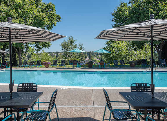 A pool with a table and chairs with umbrellas at Sunset Summit, Rocklin, CA, 95765