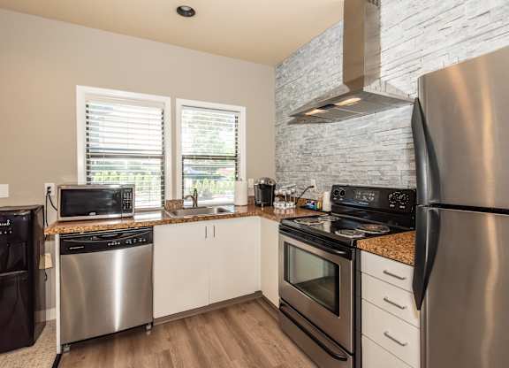 A modern kitchen with stainless steel appliances and wooden floors at Sunstone Parc, Beaverton, OR, 97008