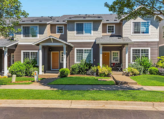A row of townhomes with green lawns and trees in front at The Landing Apartments and Townhomes, Oregon, 97045