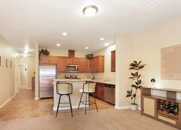 A kitchen with a refrigerator, microwave, and a dining bar with two chairs at The Landing Apartments and Townhomes, Oregon, 97045